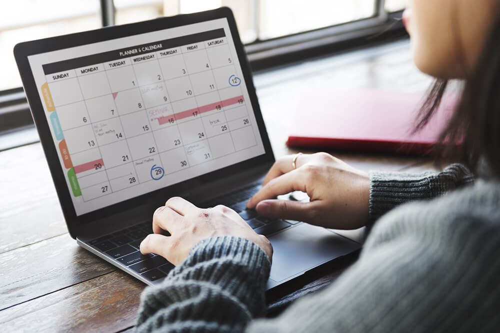 Frau am Laptop mit offenen Kalender
